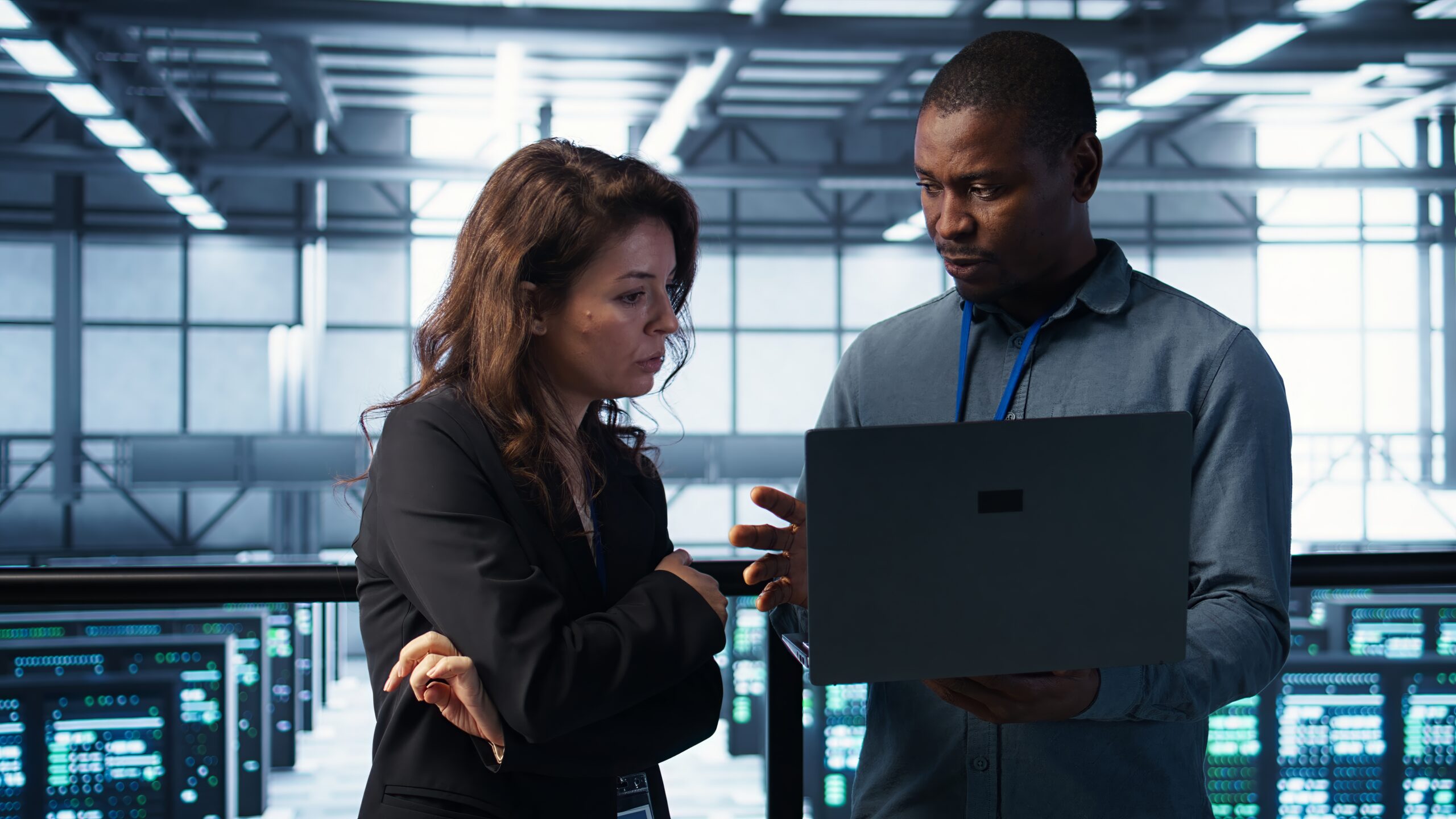 Developers in data center workspace coding on laptop, analyzing metrics, optimizing storage volumes. Teamworking IT professionals in server room using notebook, ensuring seamless operations, camera B